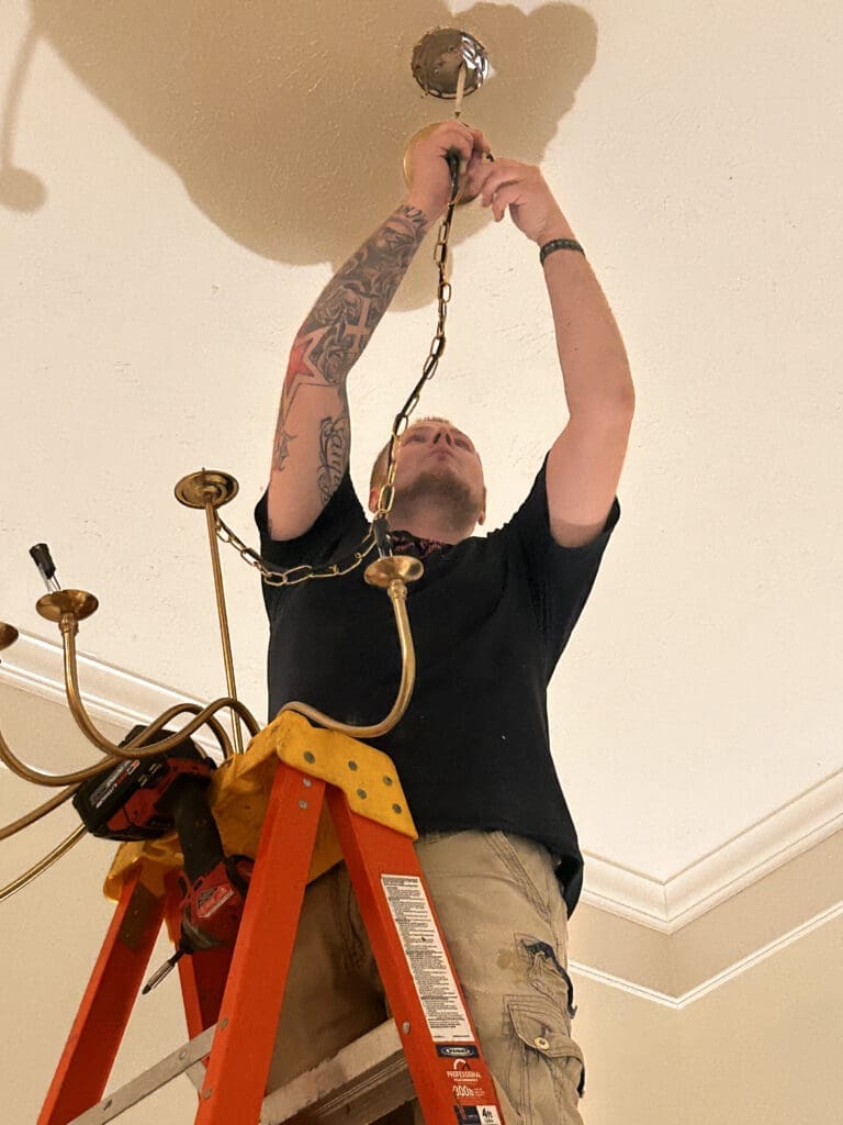 A man is hanging up the lights on the ceiling.